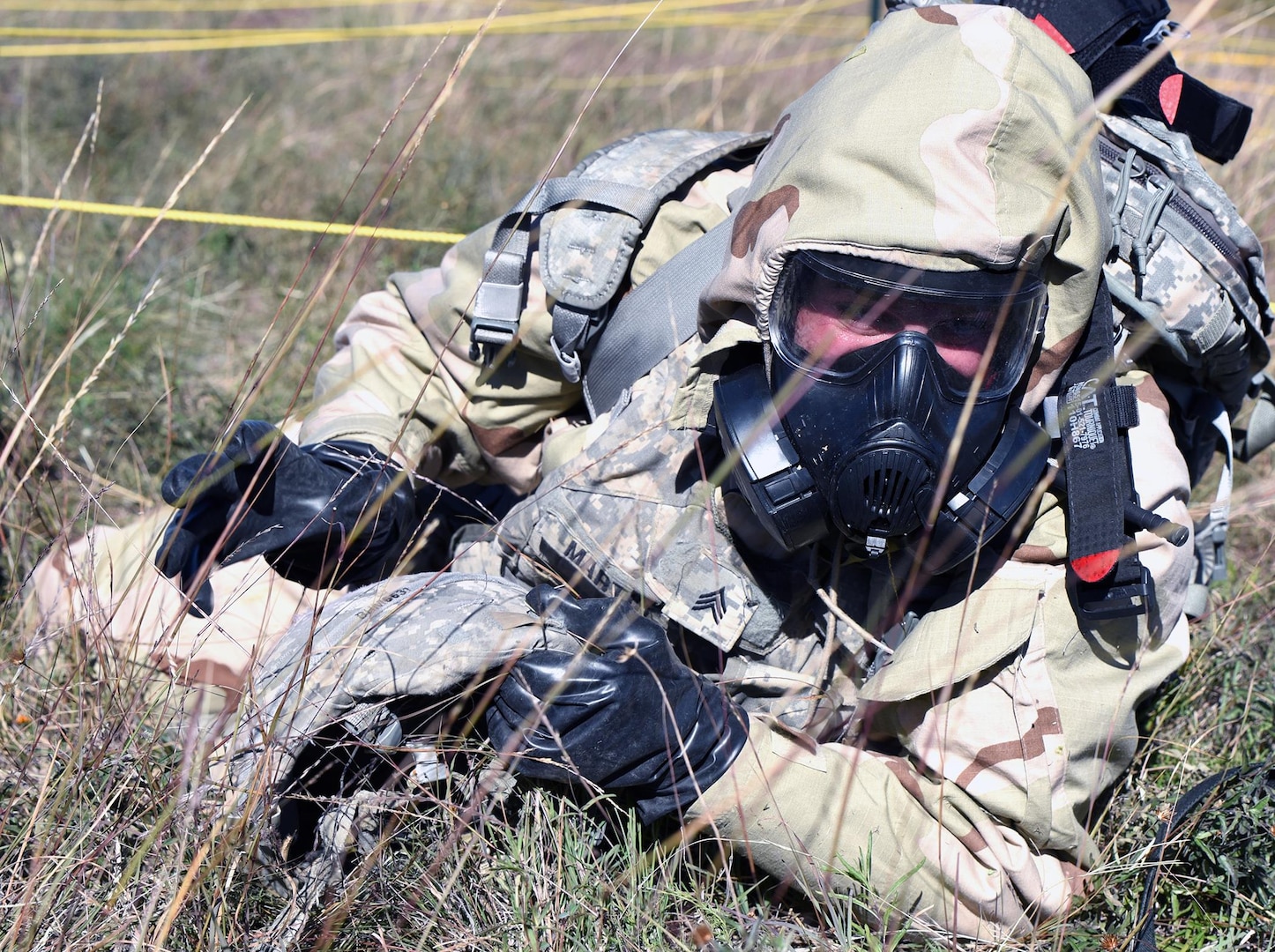 Sgt.Daniel Martin from the 1st Infantry Division low crawling though simulated wire during the chemical, biological, radiological and nuclear (CBRN) defense lane.