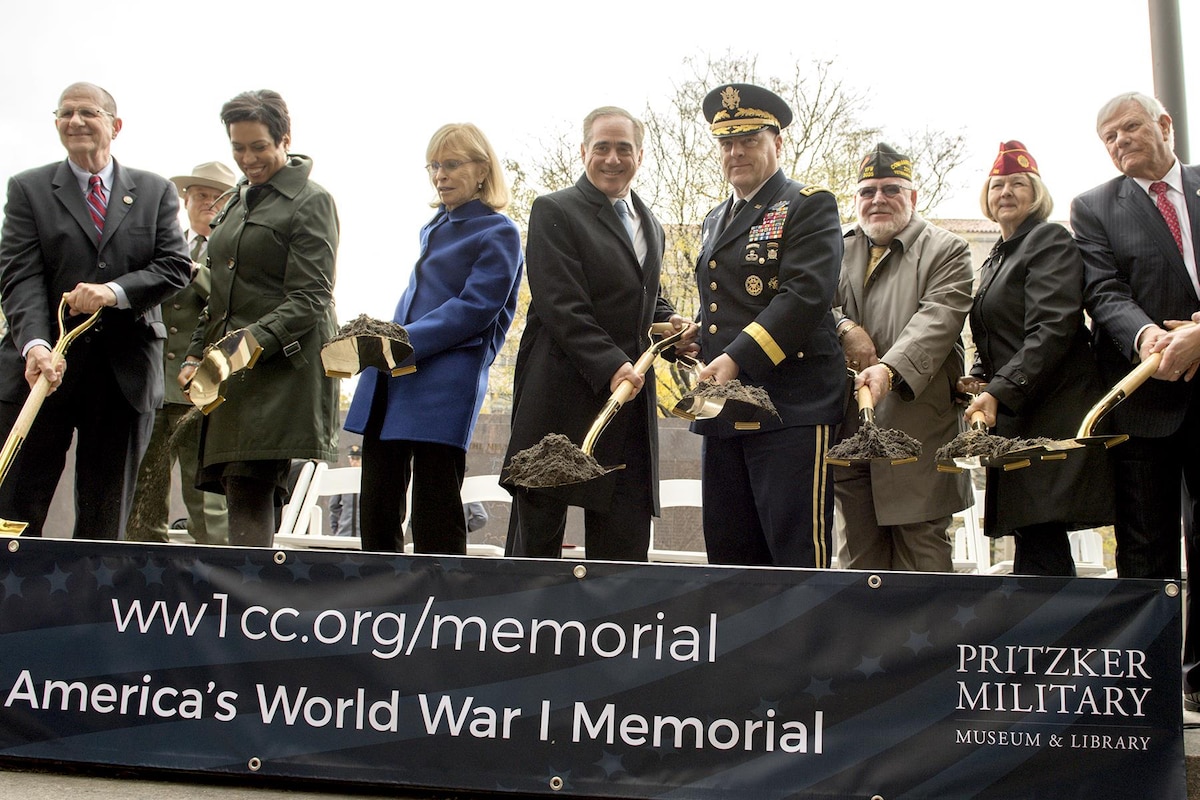 A row of people holding shovels pose for a photograph.