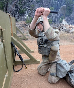 Sgt,Jonathan Zorn,  U.S. Army Alaska, chops through the simulated skin of a downed helicopter to rescue an injured Soldier