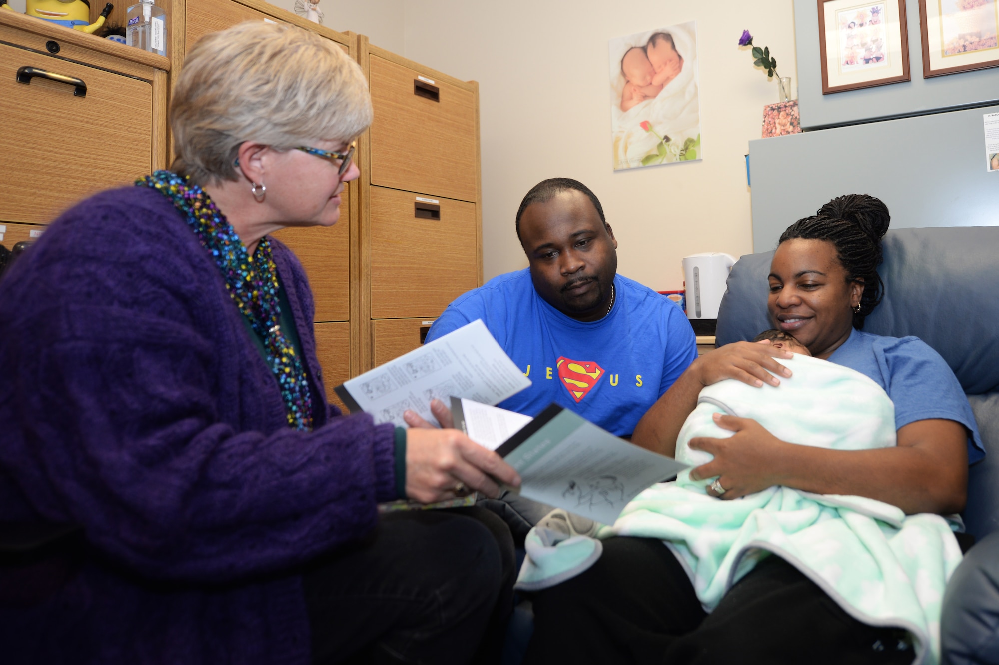 Helen Romeyn, a Family Advocacy nurse, gives informational booklets to Lei-Andrea Banks and her husband, Staff Sgt. Adrian Banks, the operations manager at the Bellamy Fitness Center, about newborns like their own, Kerrington, at Ellsworth Air Force Base, S.D., Nov. 8, 2017. The New Parent Support Program is a community-based program that serves families with children three years old and under. (U.S. Air Force photo by Airman 1st Class Thomas Karol)