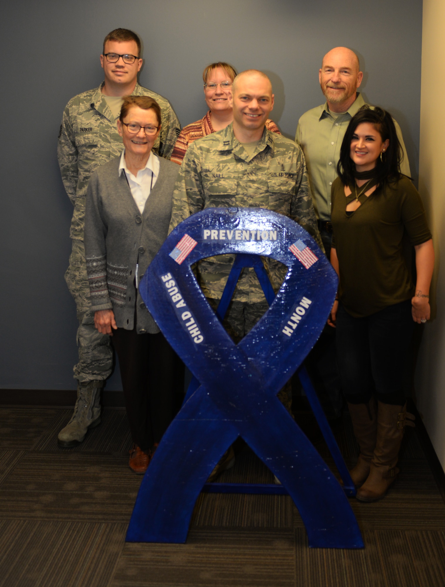 Members of the Ellsworth Air Force Base Family Advocacy Program stand next to a ribbon promoting child abuse awareness, Nov. 8, 2017. The program runs counseling, outreach, new parent support and Family Advocacy Strength-Based Therapy to empower Air Force families. (U.S. Air Force photo by Airman 1st Class Thomas Karol)