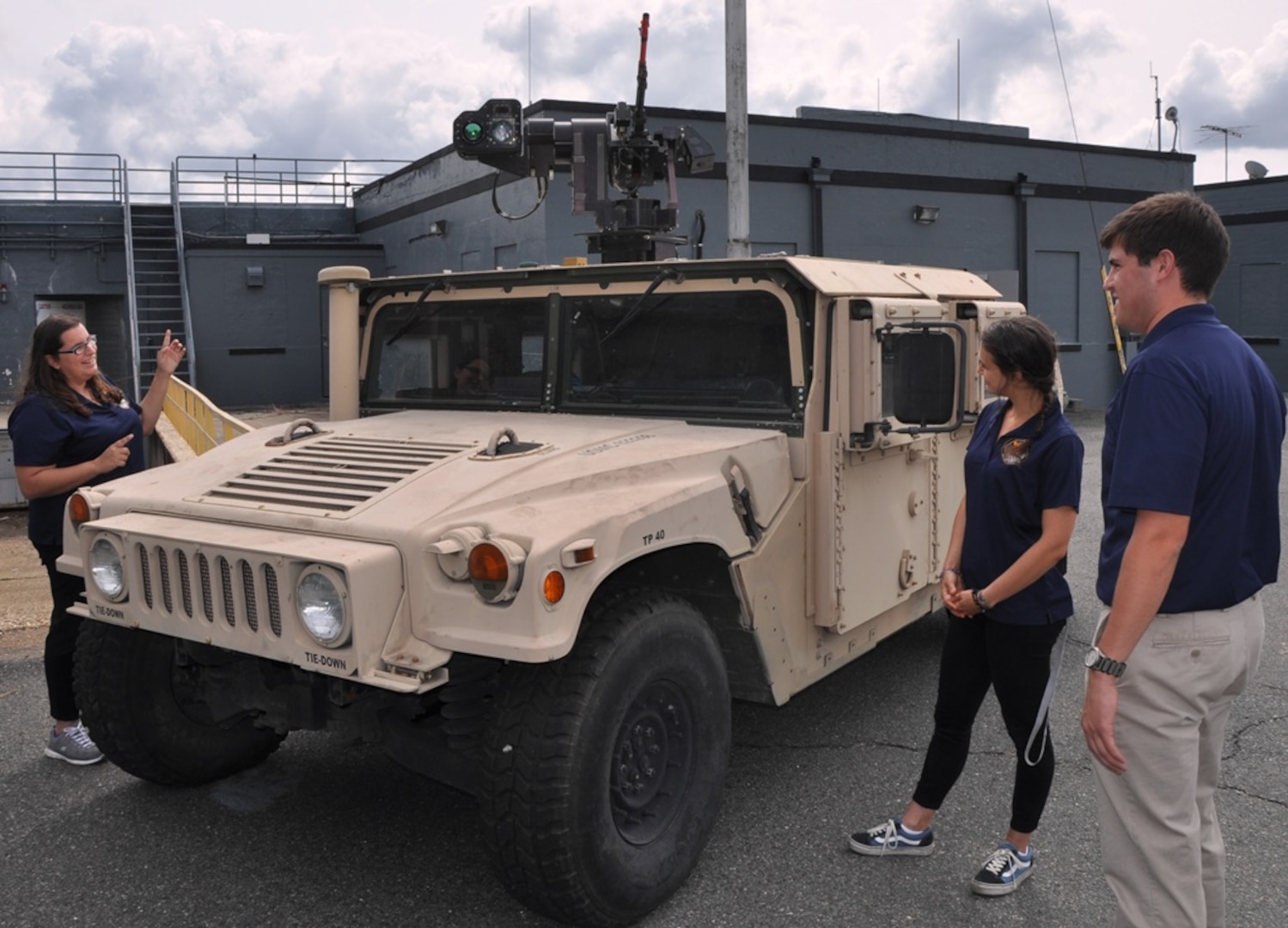 IMAGE: DAHLGREN, Va. (Sept. 12, 2017) - Salima Fenaoui, Michelle Craft, and Joe Gills, left to right, discuss the Autonomous Remote Engagement System installed on the Humvee and the capabilities it provides to the warfighter. They were among the junior scientists and engineers of Navy Sly Fox Mission 22 who developed and demonstrated the Collaborative Aerial Network for the Autonomous Remote Engagement System rapid prototyping technology for several hundred Navy civilian and military personnel who watched it detect, track, and engage targets on the Potomac River Test Range.