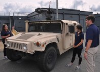 IMAGE: DAHLGREN, Va. (Sept. 12, 2017) - Salima Fenaoui, Michelle Craft, and Joe Gills, left to right, discuss the Autonomous Remote Engagement System installed on the Humvee and the capabilities it provides to the warfighter. They were among the junior scientists and engineers of Navy Sly Fox Mission 22 who developed and demonstrated the Collaborative Aerial Network for the Autonomous Remote Engagement System rapid prototyping technology for several hundred Navy civilian and military personnel who watched it detect, track, and engage targets on the Potomac River Test Range.