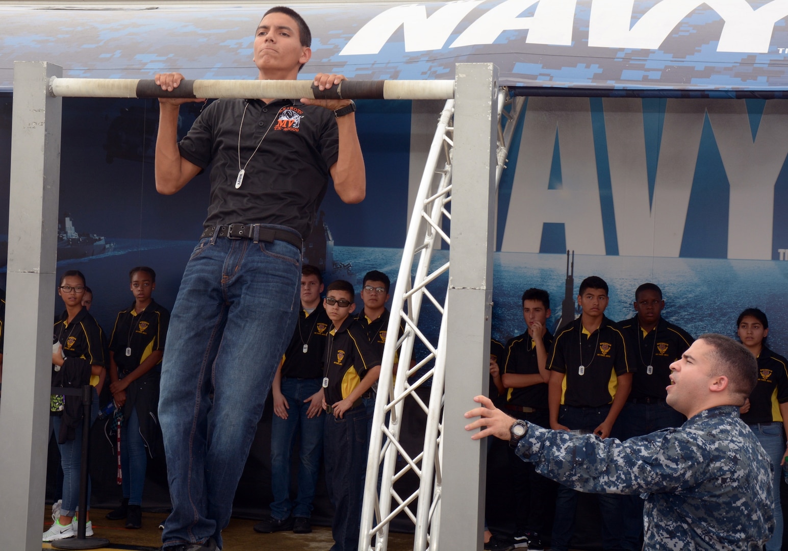 Petty Officer 1st Class John Torres monitors Jonathon Buerger, a senior attending Media Valley High School during the pull-up challenge sponsored by America’s Navy at the 2017 Joint Base San Antonio Air Show and Open House aboard JBSA-Lackland Kelly Field Annex.  Buerger, who completed 25 pull-ups, was amongst 3,200 high school students attending the pre-day rehearsals of the air show and visiting the Navy’s virtual reality experience, the “Nimitz”.  Torres, a Navy recruiter assigned to Navy Recruiting Station Mercado, Navy Recruiting District San Antonio, is a 2000 graduate of Killeen High School.