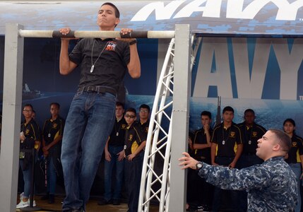Petty Officer 1st Class John Torres monitors Jonathon Buerger, a senior attending Media Valley High School during the pull-up challenge sponsored by America’s Navy at the 2017 Joint Base San Antonio Air Show and Open House aboard JBSA-Lackland Kelly Field Annex.  Buerger, who completed 25 pull-ups, was amongst 3,200 high school students attending the pre-day rehearsals of the air show and visiting the Navy’s virtual reality experience, the “Nimitz”.  Torres, a Navy recruiter assigned to Navy Recruiting Station Mercado, Navy Recruiting District San Antonio, is a 2000 graduate of Killeen High School.