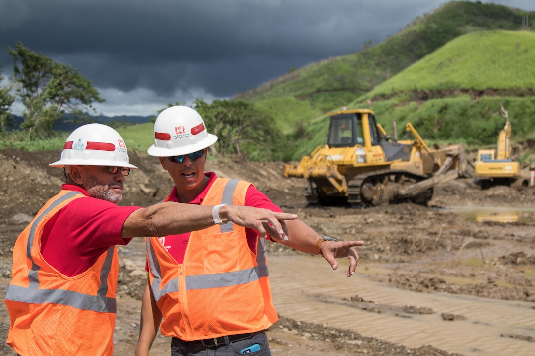 Two engineers point to a levee while discussing the project.