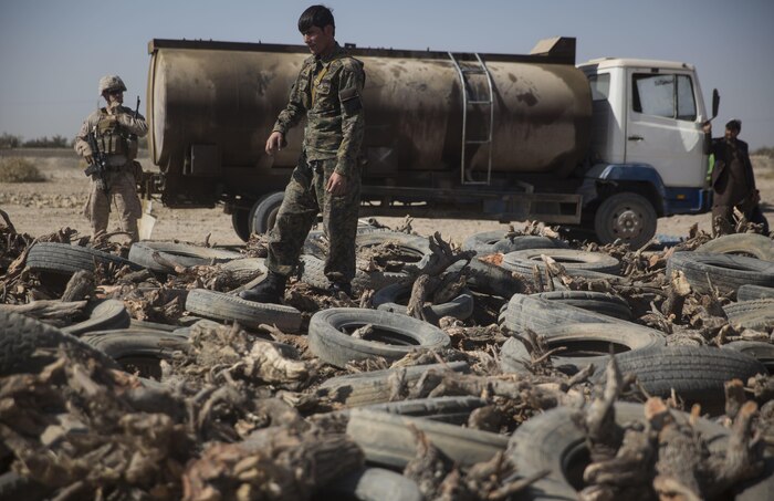 An Afghan National Policemen spreads out tires before the top layer of confiscated drugs gets added during a periodic drug burn at Bost Airfield, Afghanistan, Nov. 2, 2017. The ANP arrived with approximately three tons of confiscated drugs from court cases in Helmand Province that have been stored over the past four years. This periodic burn included opium, heroin, hashish, various chemicals, alcohol and morphine. (U.S. Marine Corps photo by Sgt. Justin T. Updegraff)