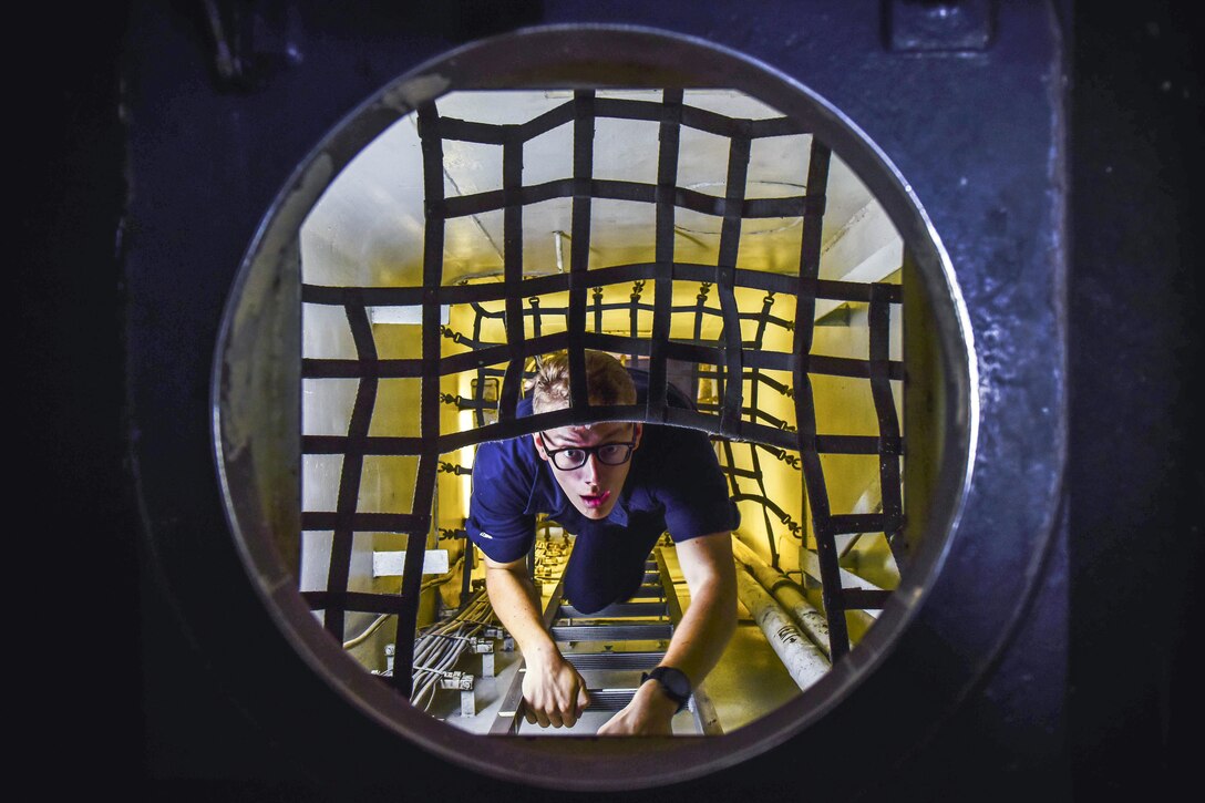 A sailor, shown from overhead, climbs a ladder toward a circular opening covered in netting.