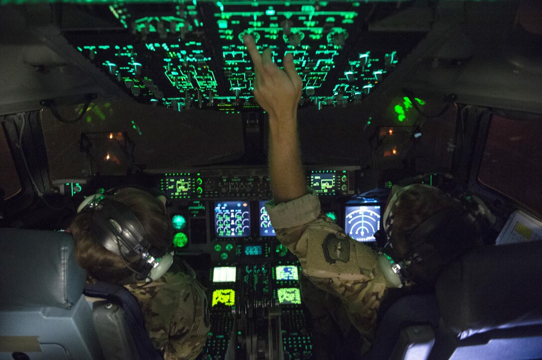 Air Force pilots work the cockpit controls of a military aircraft.