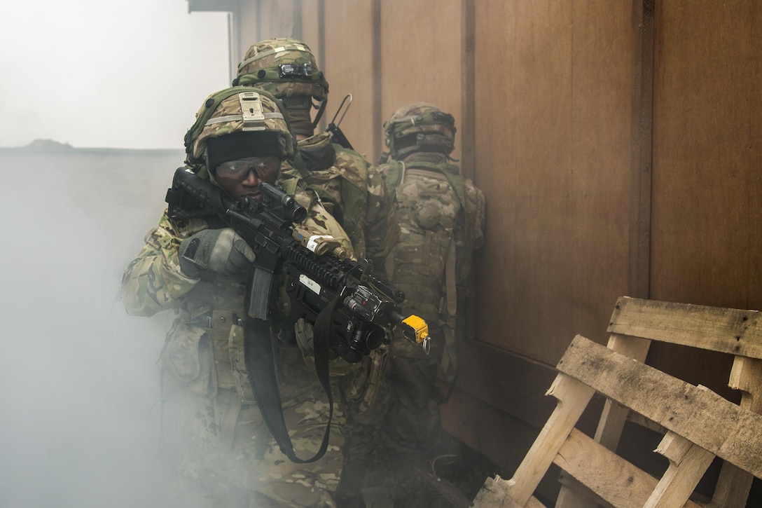 Soldiers with weapons participate in an exercise.