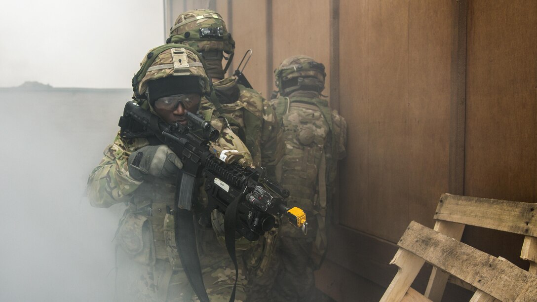 Soldiers with weapons participate in an exercise.