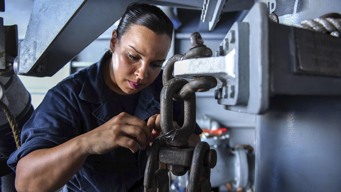 A sailor works on a piece of machinery.