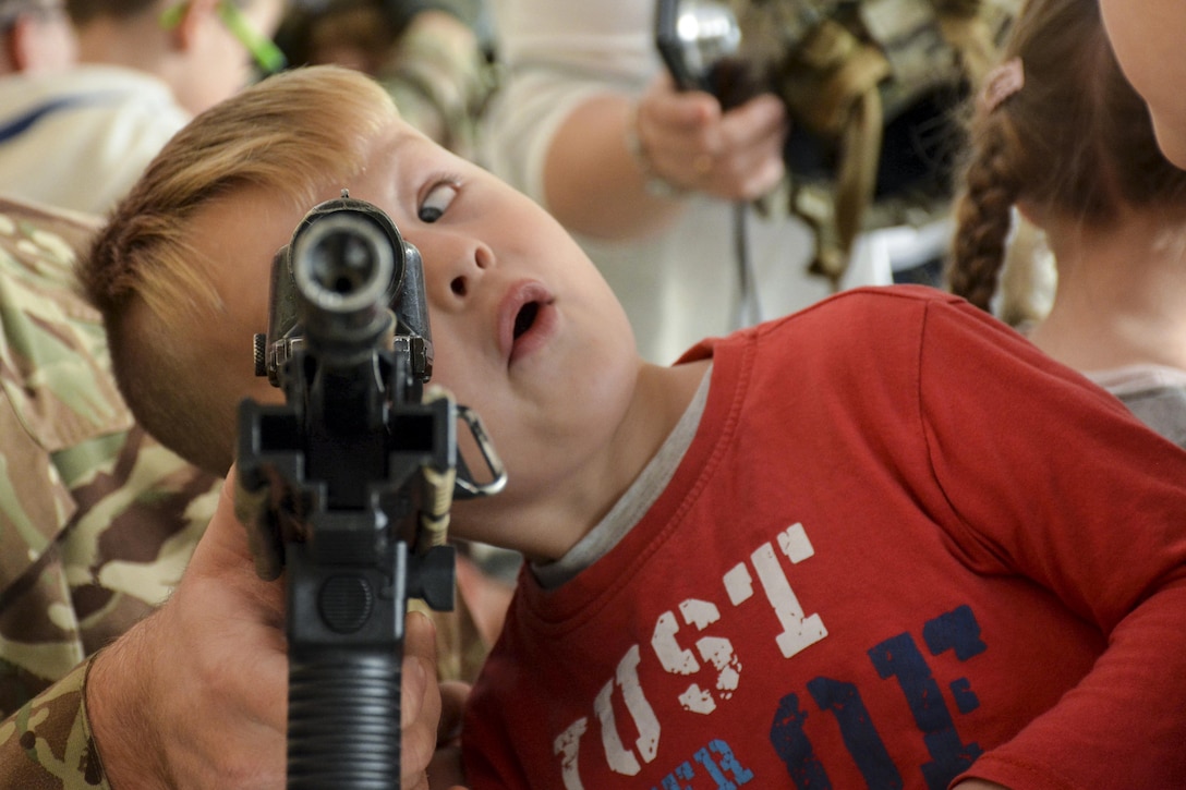 A child looked through a military assault rifle.