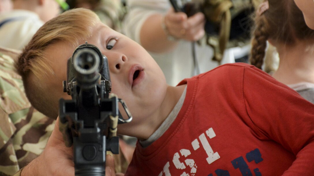 A child looked through a military assault rifle.