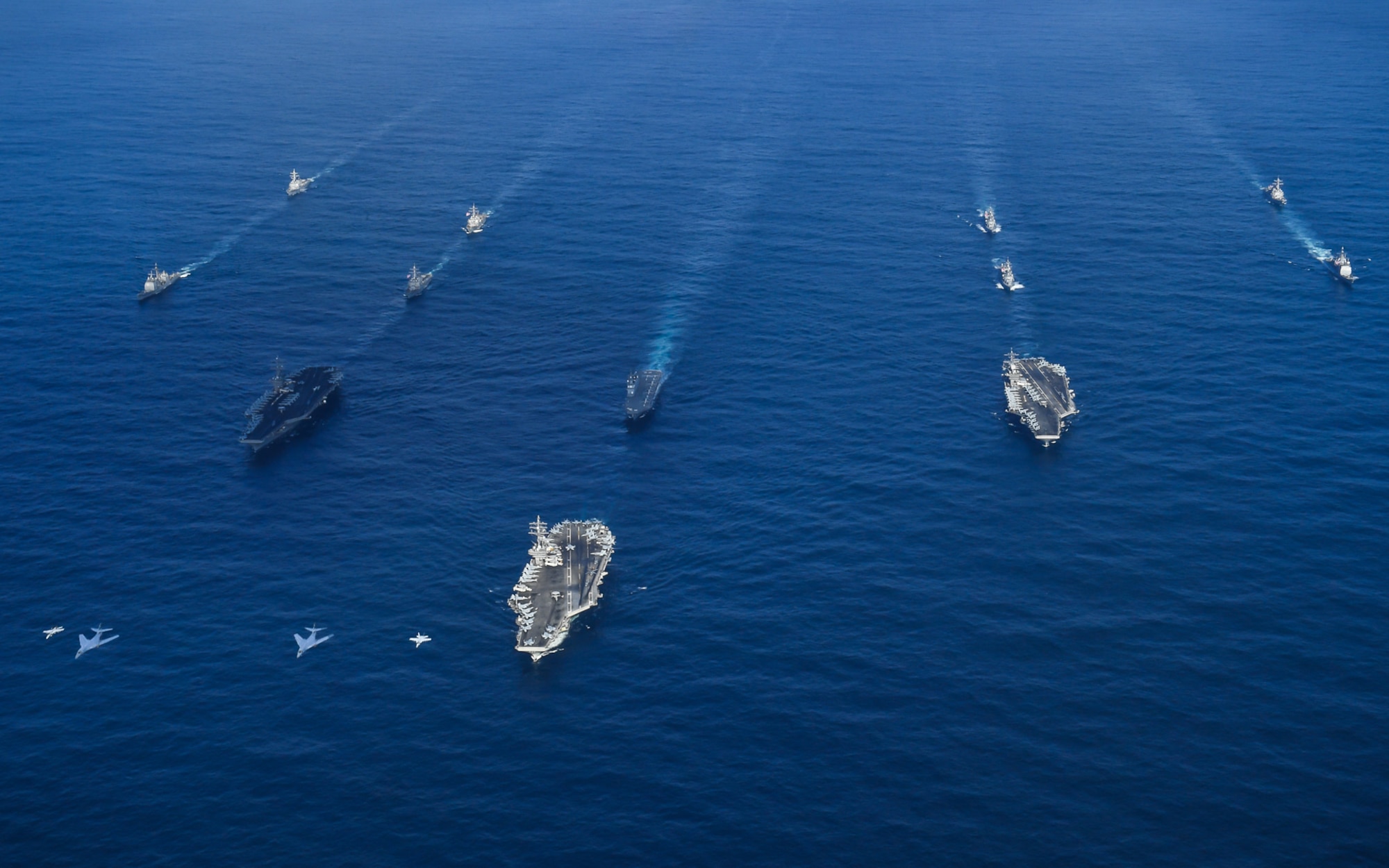 Two U.S. Air Force B-l B Lancers assigned to the 37th Expeditionary Bomb Squadron, deployed from Ellsworth Air Force Base, South Dakota, along with U.S. Navy F/A-18 Hornet fighter jets, perform a flyover of the USS Ronald Reagan (CVN 76), USS Nimitz (CVN 68), and USS Theodore Roosevelt (CVN 71) Carrier Strike Groups in the Western Pacific, Nov. 11, 2017