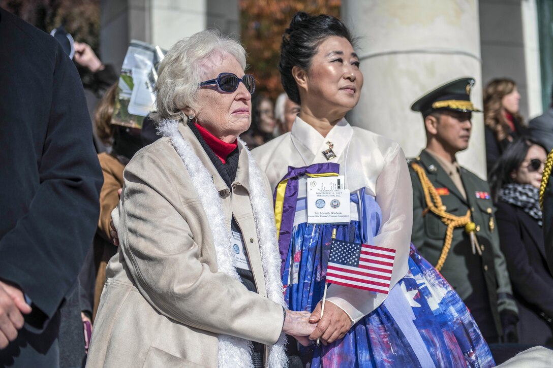 Two women hold hands outside.