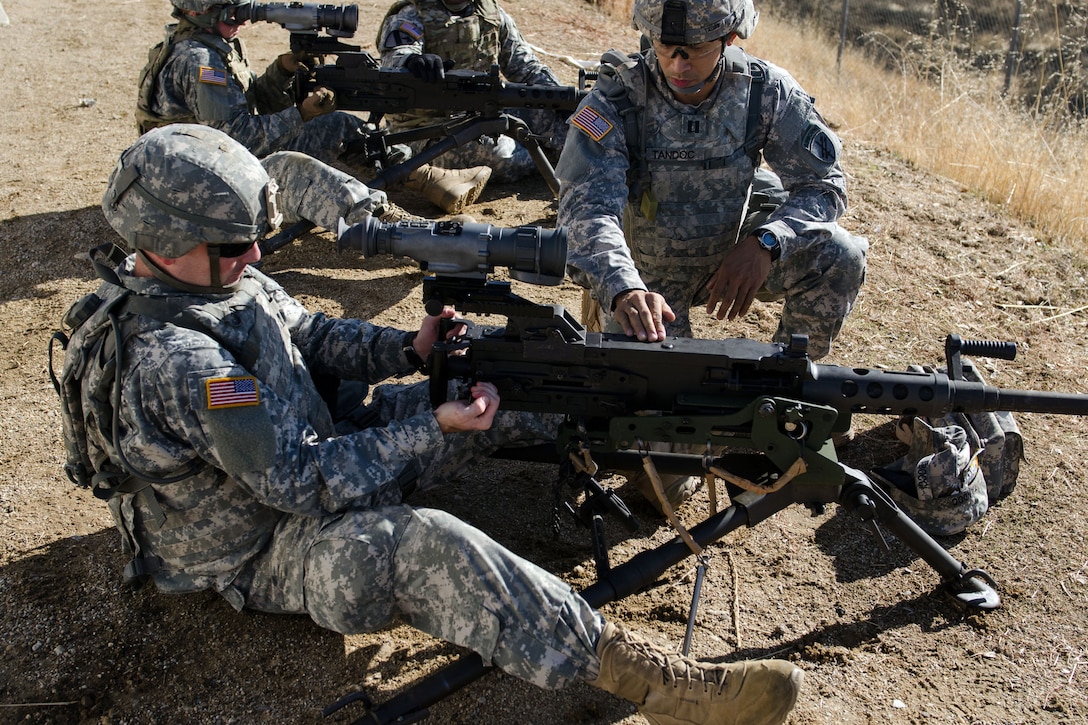 Soldiers sit around machine guns.