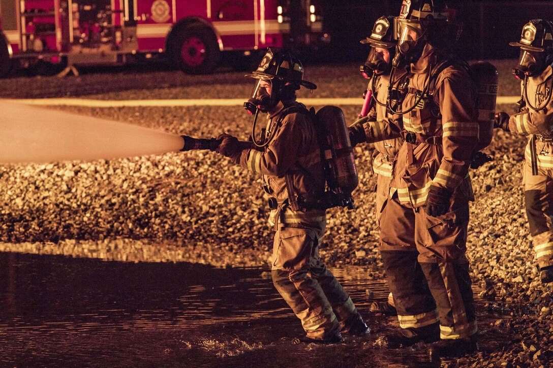 Air Force firefighters and the Valdosta Fire Department douse a blaze engulfing a training aircraft during annual nighttime firefighting training at Moody Air Force Base.