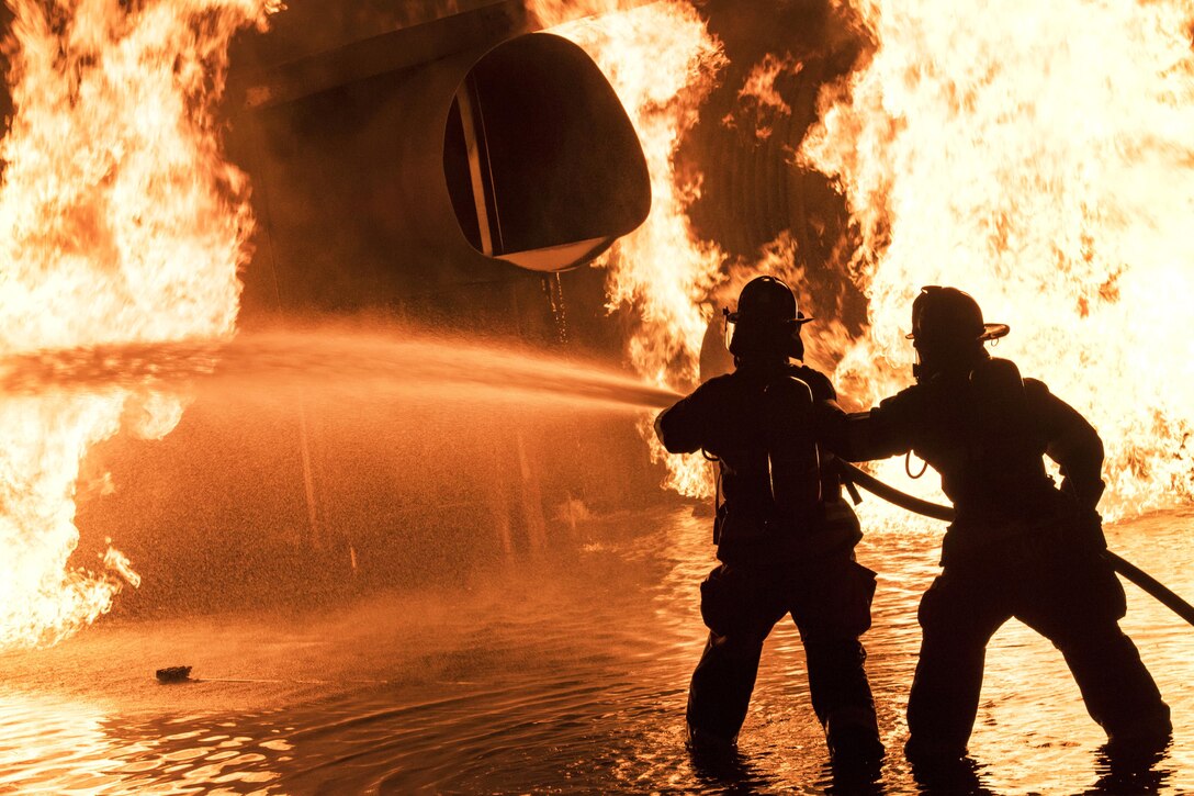 Air Force firefighters douse a blaze engulfing an aircraft during annual nighttime firefighting training at Moody Air Force Base.