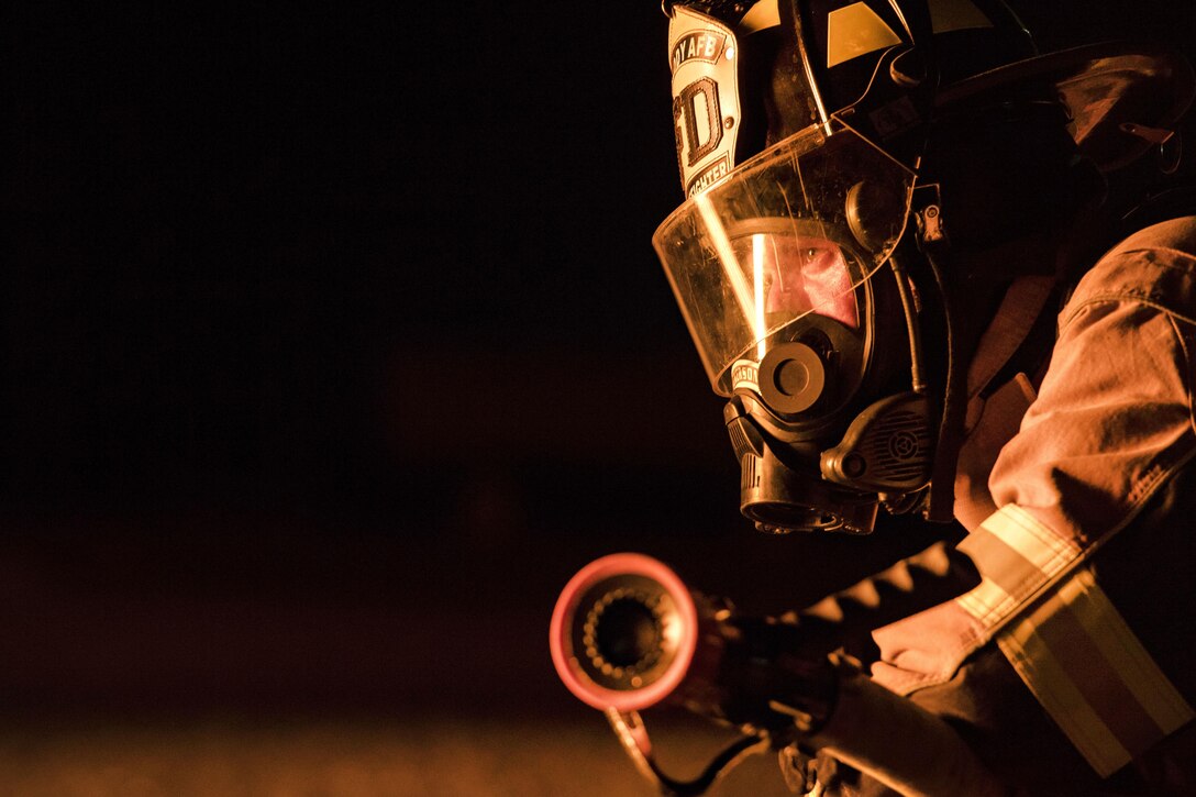 An Air Force firefighter watches as members of his team participate in nighttime firefighting training at Moody Air Force Base.