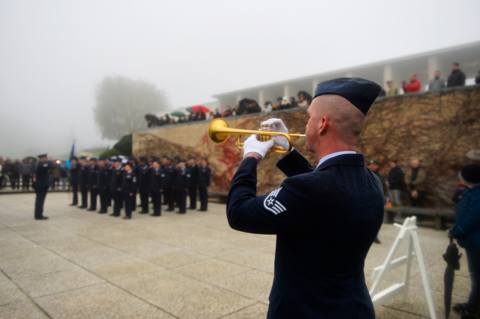 U.S. Air Force Staff Sgt. Ryan Wist, 786th Civil Engineer Squadron water and fuel systems maintenance technician, plays the bugle during a Veterans Day ceremony at Henri-Chapelle American Cemetery and Memorial, Belgium, Nov. 11, 2017. Despite inclement weather, more than 100 veterans and civilians turned up for the ceremony. (U.S. Air Force photo by Airman 1st Class Joshua Magbanua)