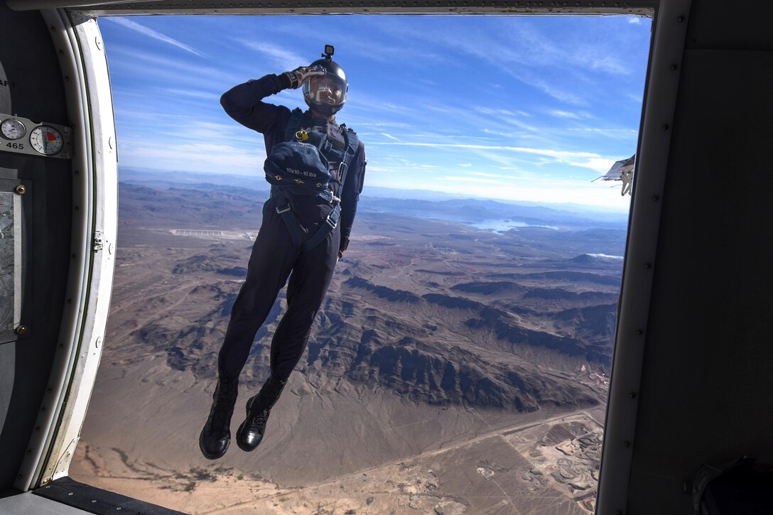 An airman jumps out of an airplane and salutes.