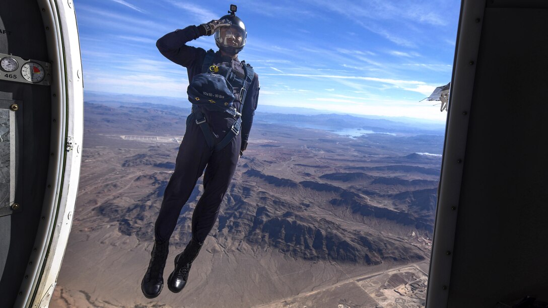 An airman jumps out of an airplane and salutes.