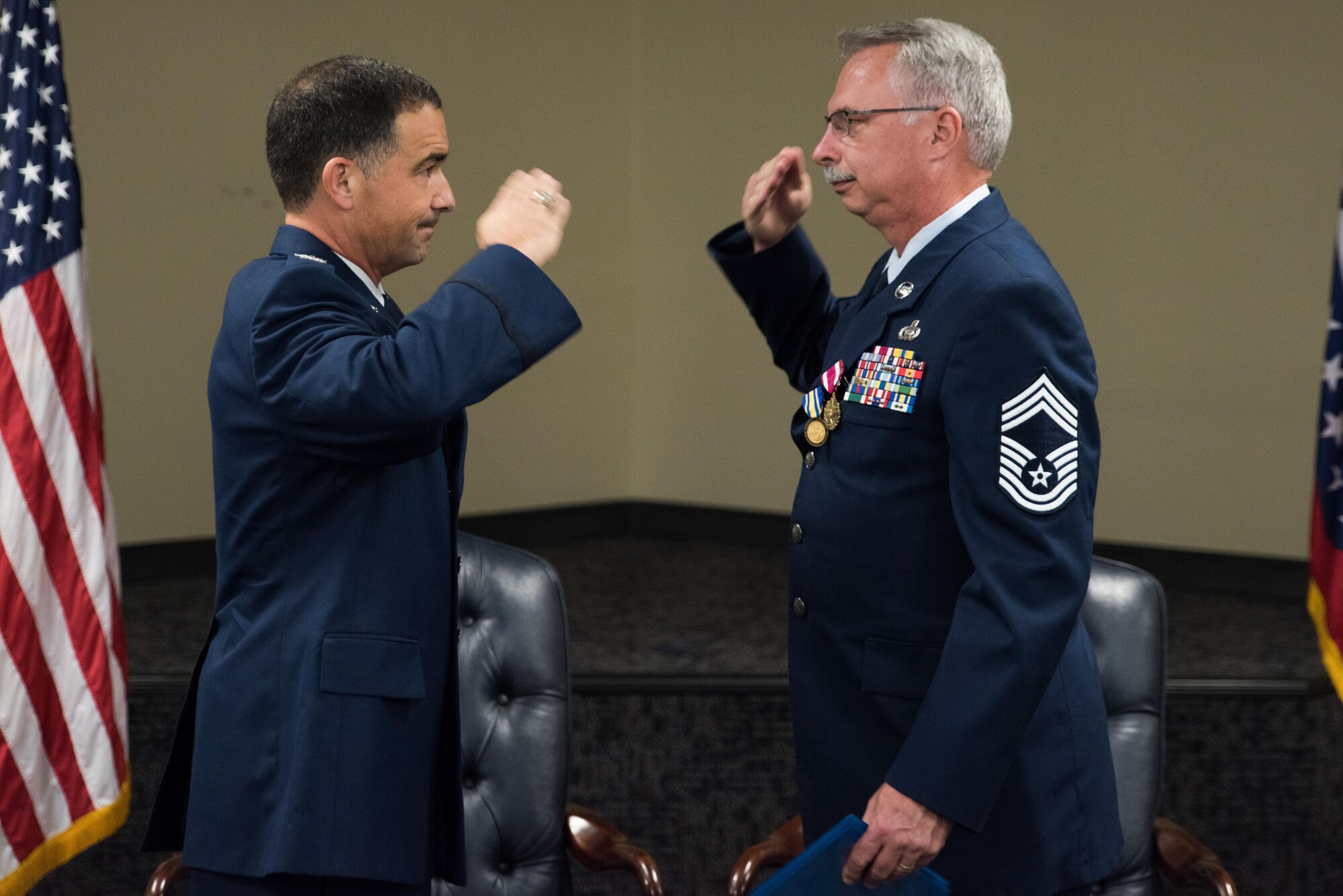 Senior Master Sgt. James Rivers, Superintendent 123rd Intelligence Squadron, presents Chief Master Sgt. Tomi Allinder with a commiserative rifle during his retirement ceremony, Fort Smith, Ark. Allinder served 33 years in the Arkansas Air National Guard’s 123rd Intelligence Squadron before retiring as superintendent, Nov. 04, 2017. (U.S. Air National Guard photo by Tech. Sgt. Daniel Condit)