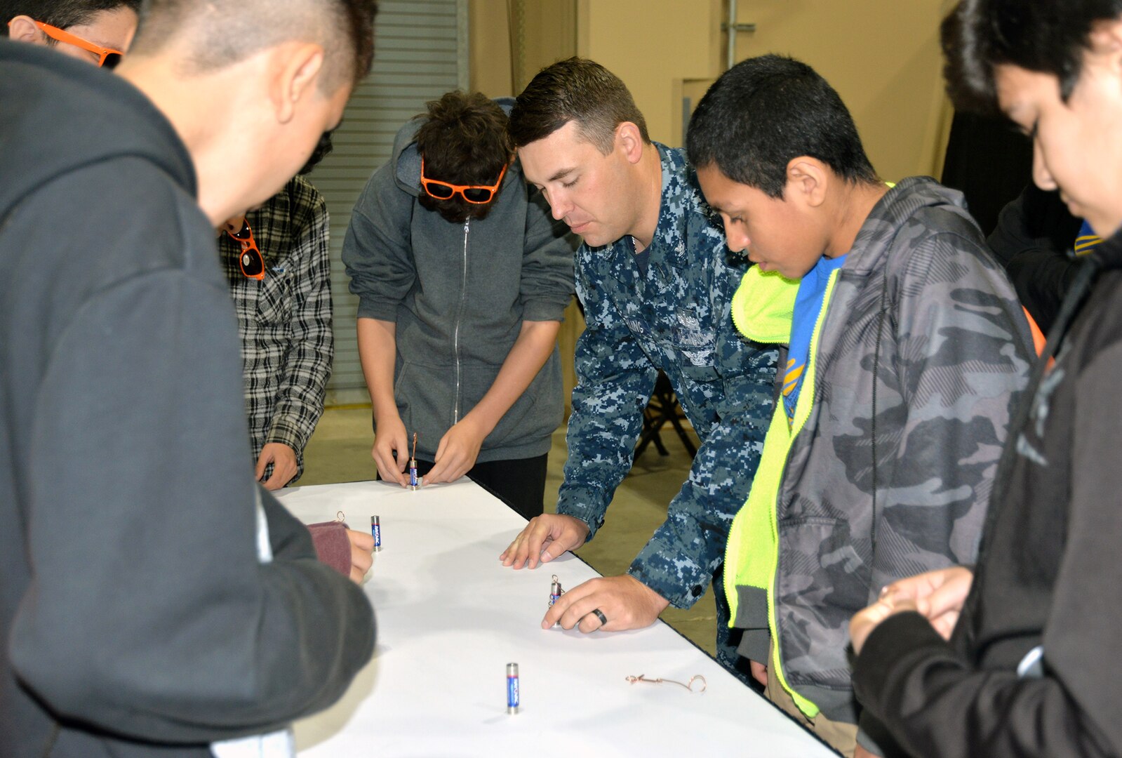 Petty Officer 2nd Class Pete Darling, Navy Recruiting District San Antonio nuclear scout for the Austin area, demonstrates to middle school students how a battery that has magnets and copper wire attached to it produces a motion that moves and rotates the copper wire at the 8th Annual San Antonio Hispanic Chamber of Commerce CORE4 STEM Expo Nov. 8 at the Freeman Expo Hall.