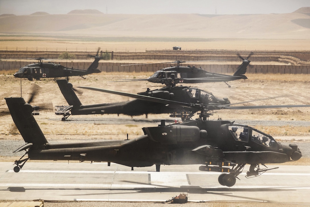 Army helicopters prepare for a mission on a runway in Afghanistan.