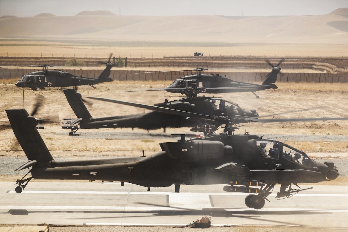Army helicopters lift off from a runway in Afghanistan