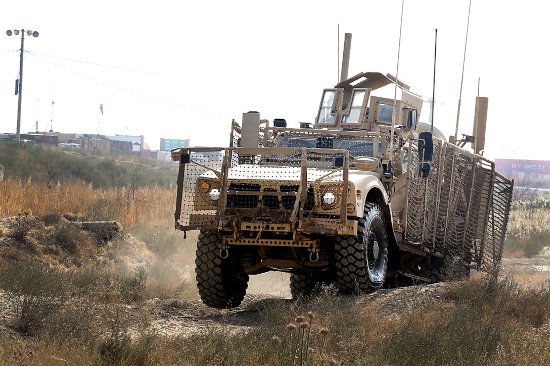 A soldier drives a mine-resistant, ambush-protected vehicle over an uneven road during a master driver training course.