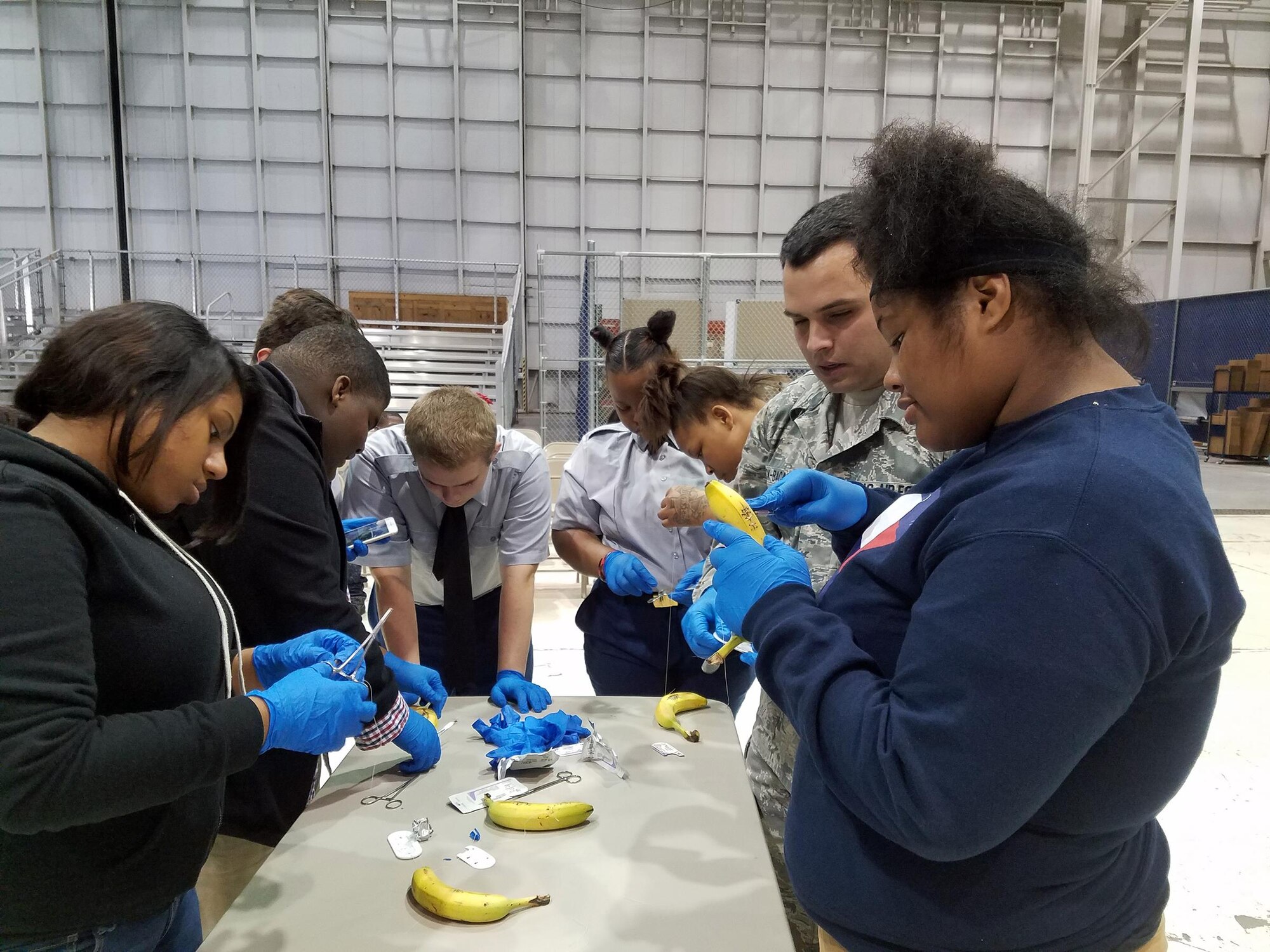 Staff Sgt. Christopher Bock-Bacalao, 445th Aerospace Medicine Squadron medical technician, watches over students from Thurgood Marshall and Meadowdale High Schools as they practice suturing by using a banana during the Dayton public schools outreach event the 445th Airlift Wing hosted Oct. 20, 2017.