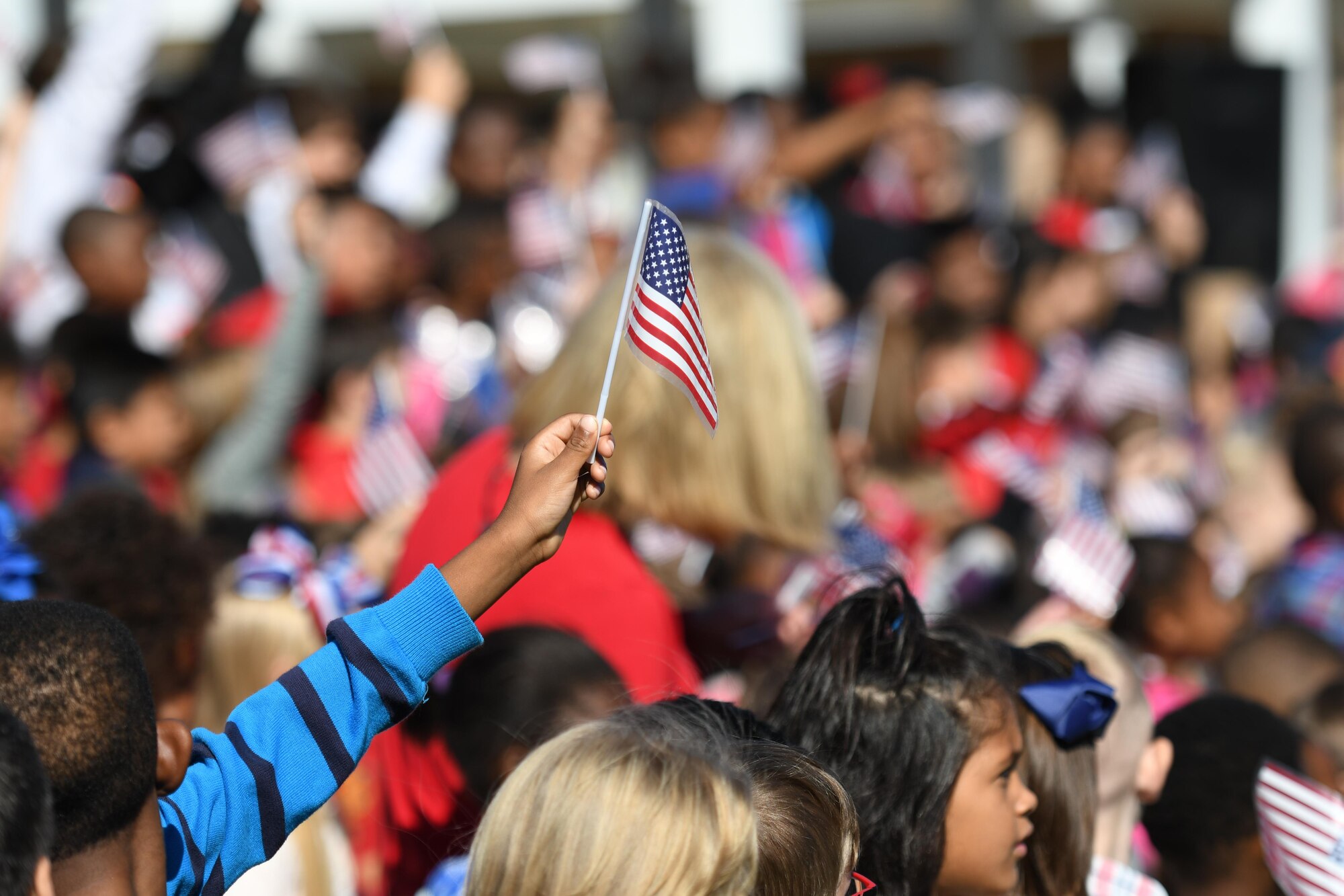 Students at Jeff Davis Elementary School wave their flags during a Veterans Day celebration Nov. 10, 2017, in Biloxi, Mississippi. During the event, students recited the Pledge of Allegiance and sang several patriotic songs. Keesler Air Force Base leadership, honor guardsmen and base personnel attended the event. (U.S. Air Force photo by Kemberly Groue)