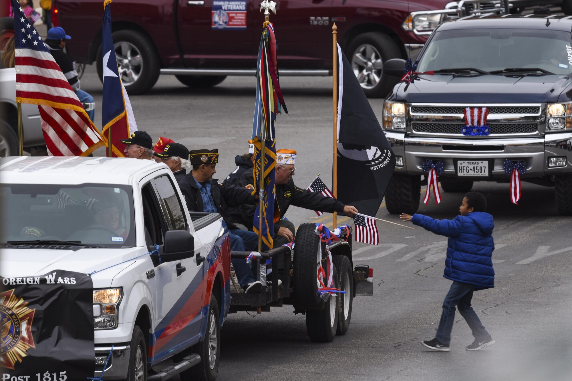 A member of the local Veterans of Foreign Wars gives a flag to a child during the Veteran’s Day Parade in San Angelo, Texas, Nov. 11, 2017. The attending VFW members came from different services and wars, including World War II, Korea and Vietnam. (U.S. Air Force photo by Airman 1st Class  Zachary Chapman/Released)