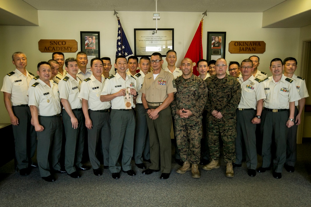 Marines and members of the Japan Ground Self Defense Force pose for a group photo after an educational event held at the Staff Noncommissioned Officer Academy, Camp Hansen, Okinawa, Japan on Nov. 8, 2017.The event was held to educate service members of the JGSDF about the Marine Corps rank structure and the roles and duties of a senior enlisted service member. (U.S. Marine Corps photo by Cpl. Jorge A. Rosales)