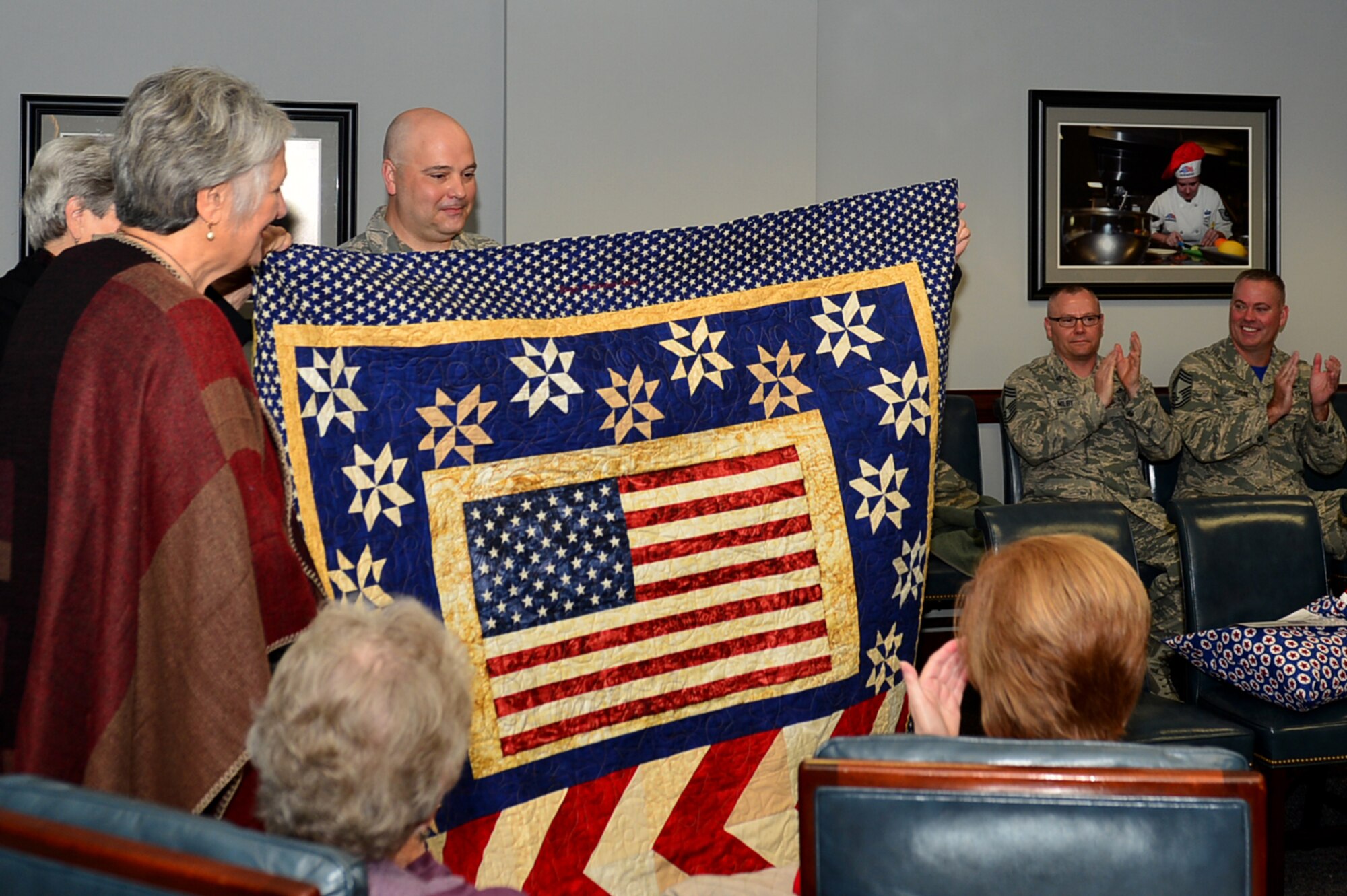 U.S. Air Force Chief Master Sgt. Thomas Boslet, 20th Operations Group superintendent, displays the quilt for Capt. Salvador Cruz, 20th Fighter Wing F-16CM Fighting Falcon pilot, during a Quilts of Valor Foundation event at Shaw Air Force Base, South Carolina, Nov. 9, 2017.