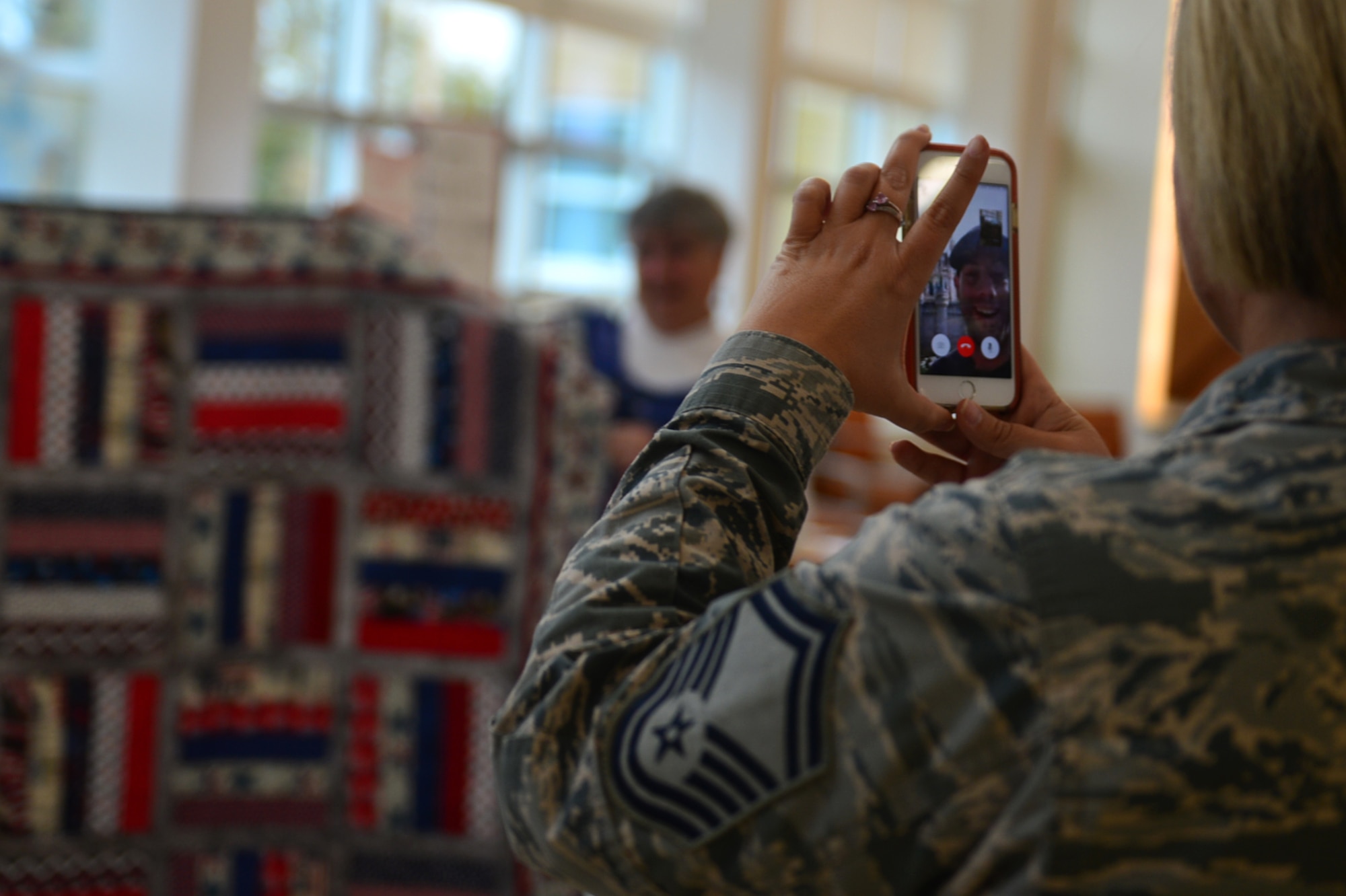 U.S. Air Force Senior Master Sgt. Heather Gulsby, 20th Medical Operations Squadron (MDOS) superintendent, video calls Airman 1st Class Daniel Caraglio, 20th MDOS mental health technician, to show him his quilt during a Quilt of Valor Foundation event at Shaw Air Force Base, South Carolina, Nov. 9, 2017.