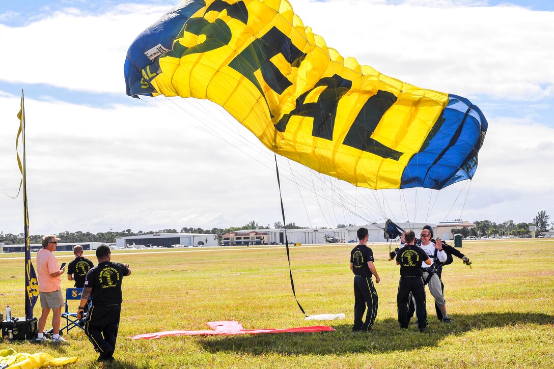Troy McDonald, right, mayor of Stuart, lands with members of the U.S. Navy Parachute Team, the Leap Frogs, after a tandem jump.