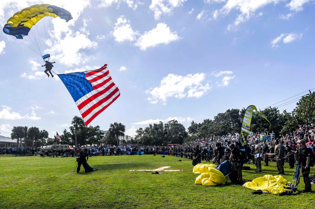 Retired Navy SEAL Jim Woods, a member of the U.S. Navy Parachute Team, the Leap Frogs, presents the American flag to spectators.