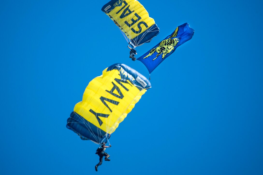 Navy Petty Officer 1st Class Brandon Peterson, top, a member of the U.S. Navy parachute team, the Leap Frogs, flies the Navy SEAL trident flag.