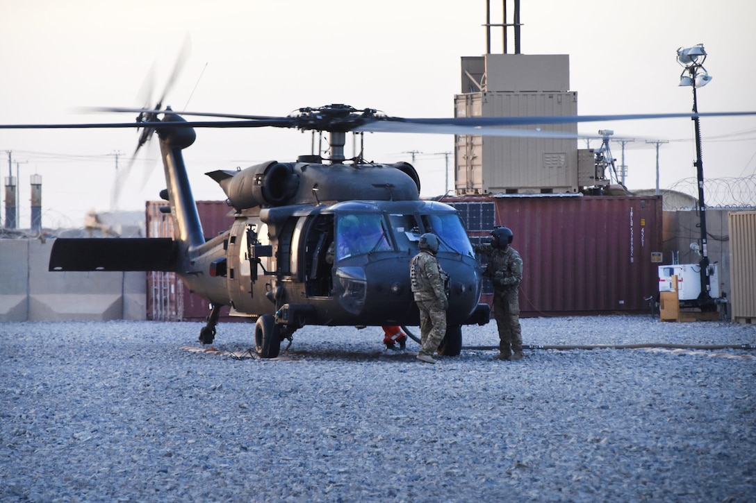 Army crew chiefs perform final pre-flight checks on their UH-60 Black Hawk helicopter before transporting soldiers and supplies.