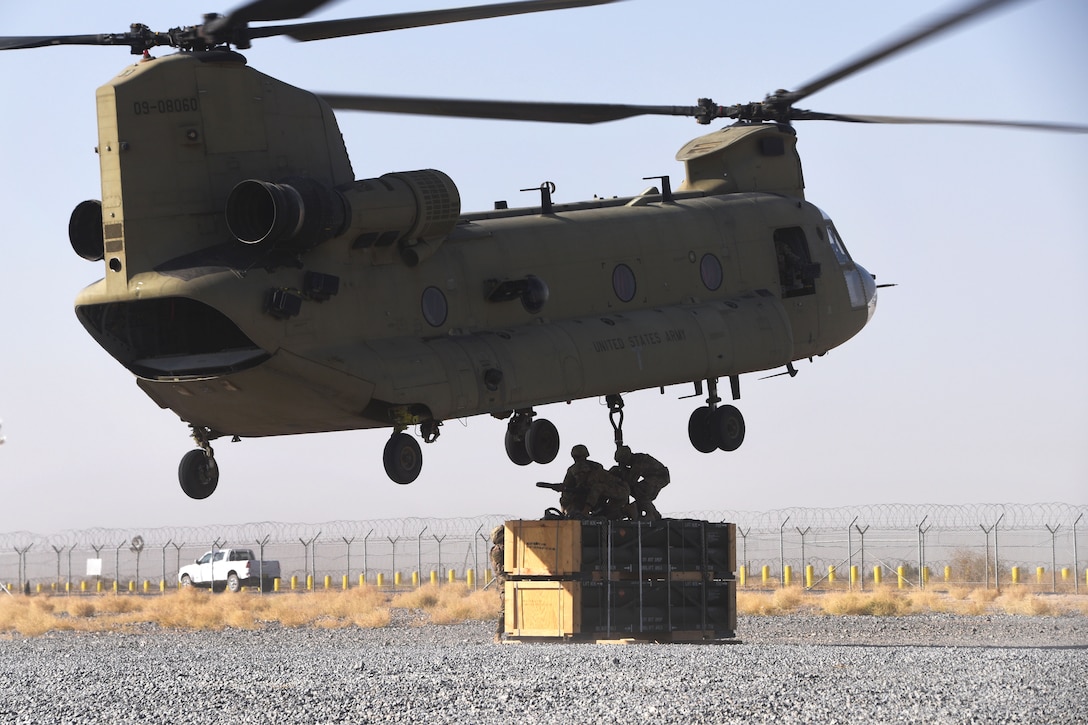 Soldiers prepare to hook-up a pallet of supplies to a CH-47 Chinook helicopter during slingload operations.