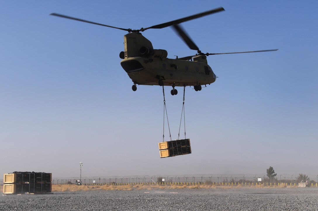 A CH-47 Chinook helicopter takes off after receiving a pallet of supplies during slingload operation at Bagram Airfield.