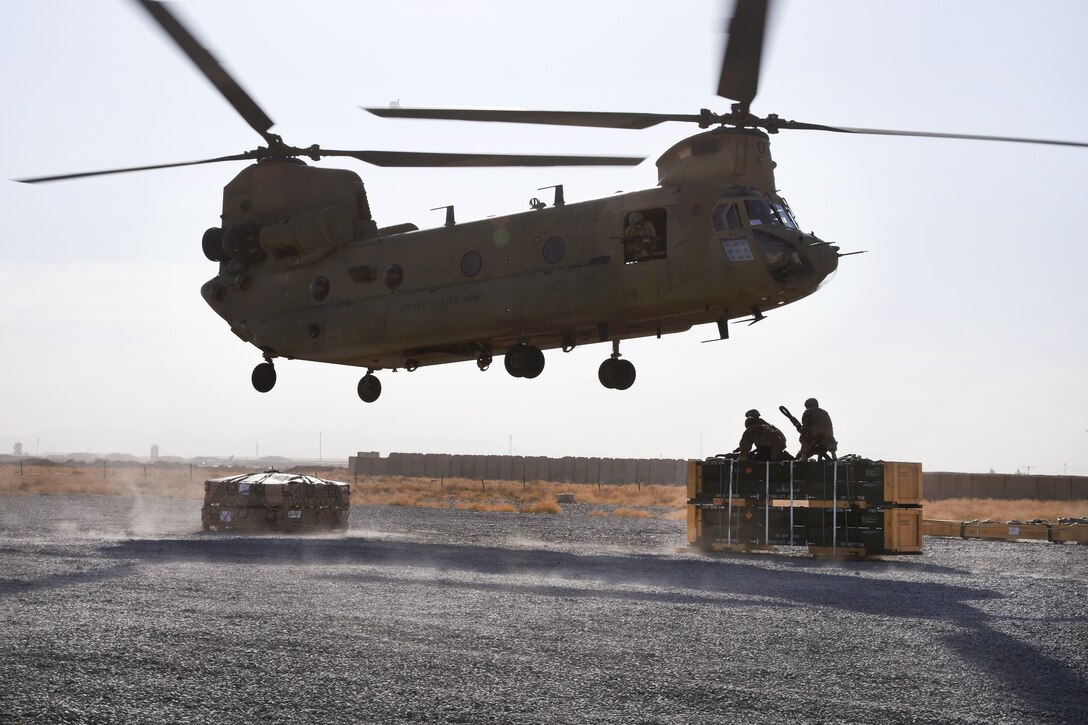 Soldiers prepare to hook-up a pallet of supplies to an approaching CH-47 Chinook helicopter during slingload operation.