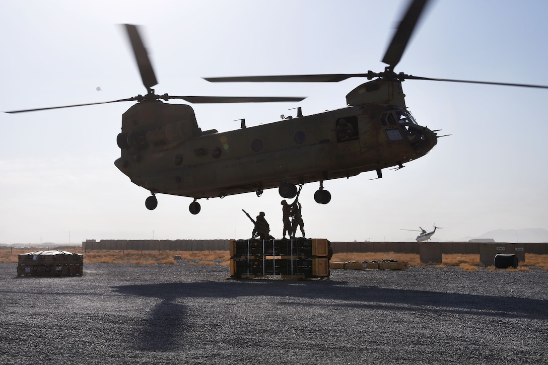 Soldiers hook-up a pallet of supplies to a CH-47 Chinook helicopter during slingload operation.
