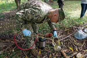 A service member sprays insecticide.