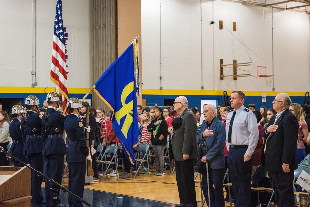 Retired Lt. Col. Clarence Wolgemuth, third from right, stands during the national anthem as the Caesar Rodney High School Air Force Junior Reserve Officer Training Corps Honor Guard presents the Colors Nov. 9, 2017, at Dover Air Force Base Middle School on Dover AFB, Del. During the Veterans Day celebration, students recognized Wolgemuth as this year’s DAFBMS Veteran of Honor. (U.S. Air Force photo by Roland Balik)