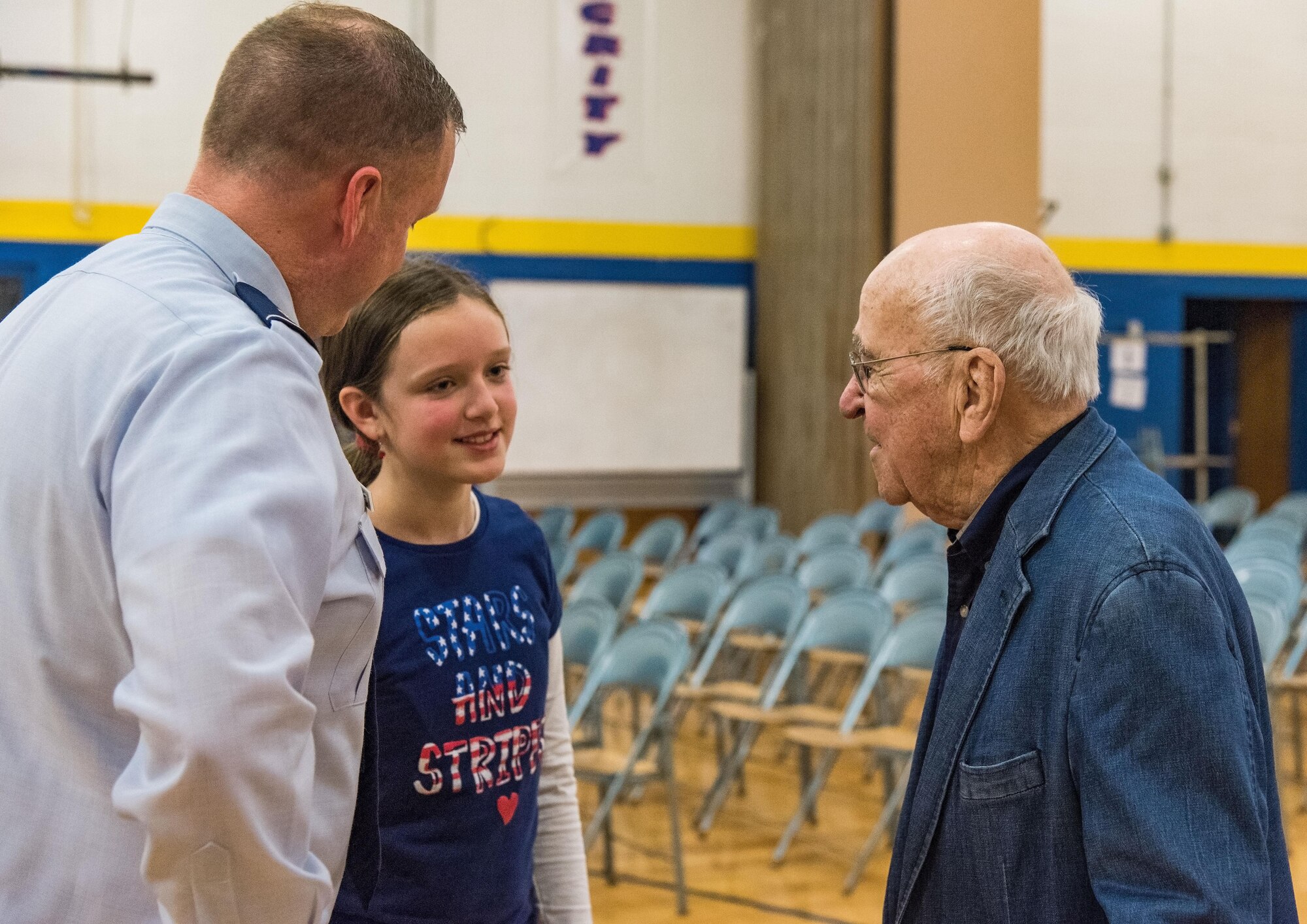 Sixth grade student Emily Goeke, center, daughter of Maj. Robert Goeke, 436th Contracting Squadron commander, left, speaks with retired Lt. Col. Clarence Wolgemuth, right, after the Veterans Day ceremony Nov. 9, 2017, at Dover Air Force Base Middle School on Dover AFB, Del. Wolgemuth, the 2017 DAFBMS Veteran of Honor, met with students and faculty after the ceremony. (U.S. Air Force photo by Roland Balik)