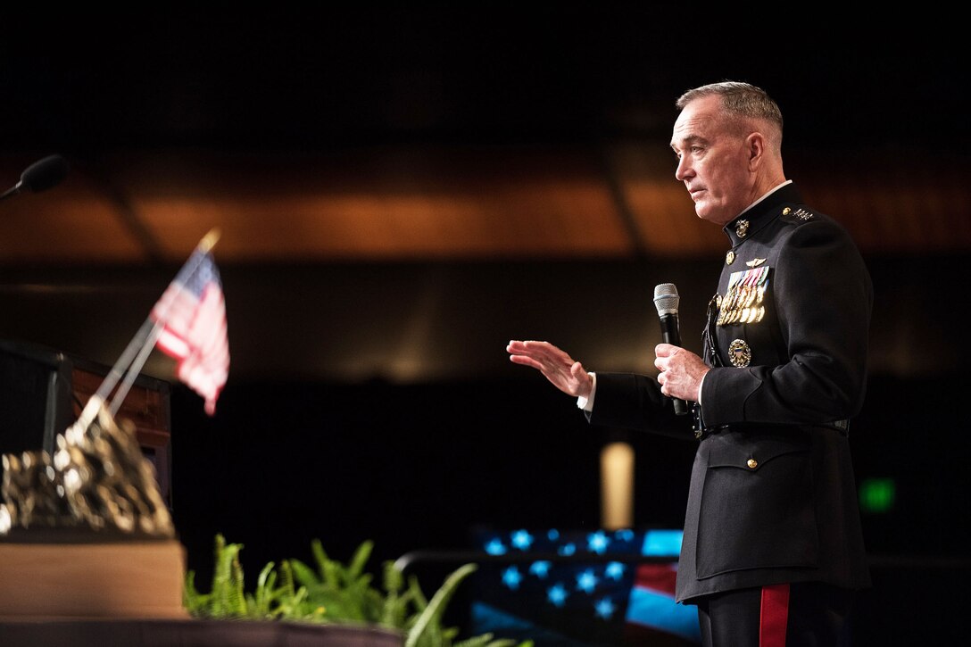 Marine Corps Gen. Joe Dunford holds microphone while making remarks.